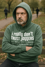 Man wearing a green hoodie with text sitting on a bench in a park.