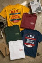 Five t-shirts with D.B.S. logo on a textured surface with books and a mug.
